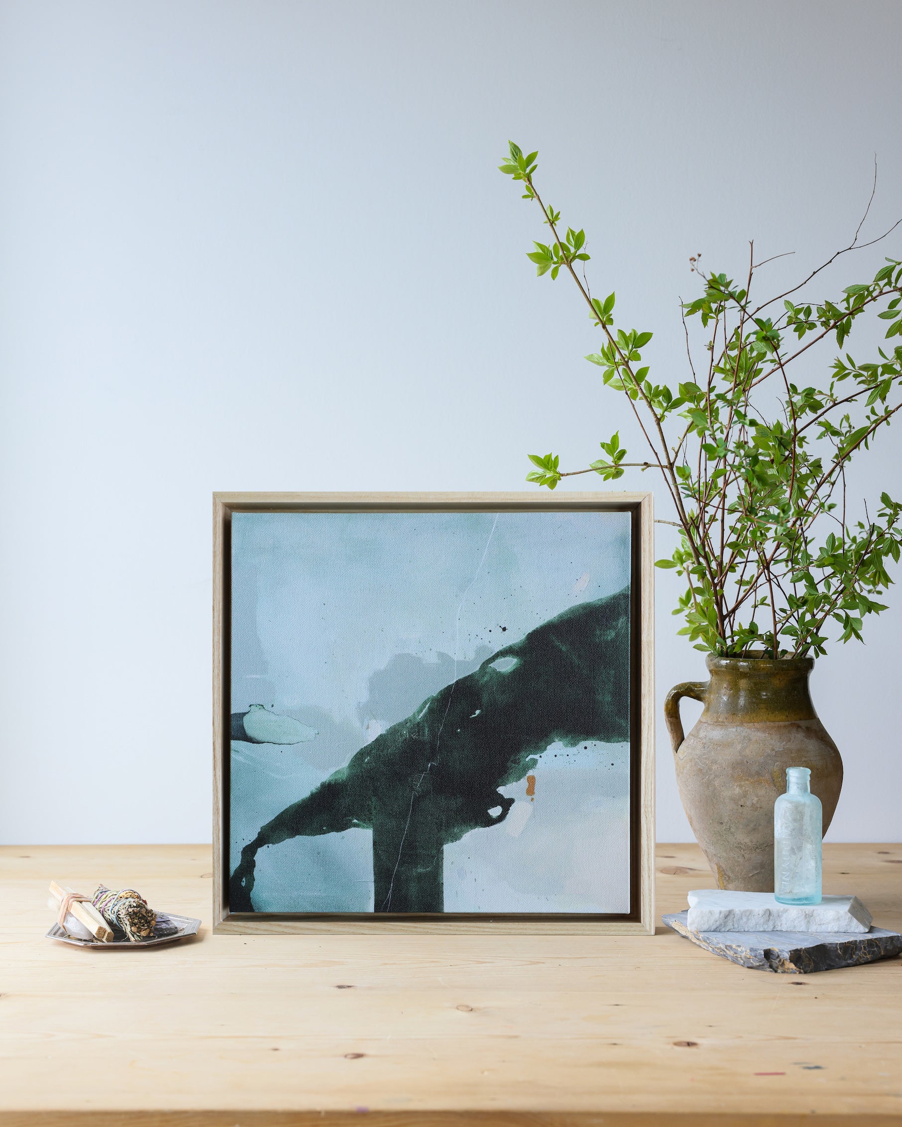 Framed artwork of a whale on a wooden surface with a vase and decorative items.